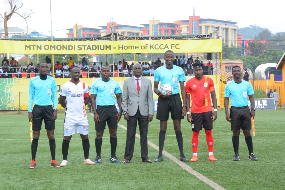 Tonny Mawejje in a white kit standing with Gavin Kizito and match officials before the testimonial match at Lugogo, 14 September 2022.