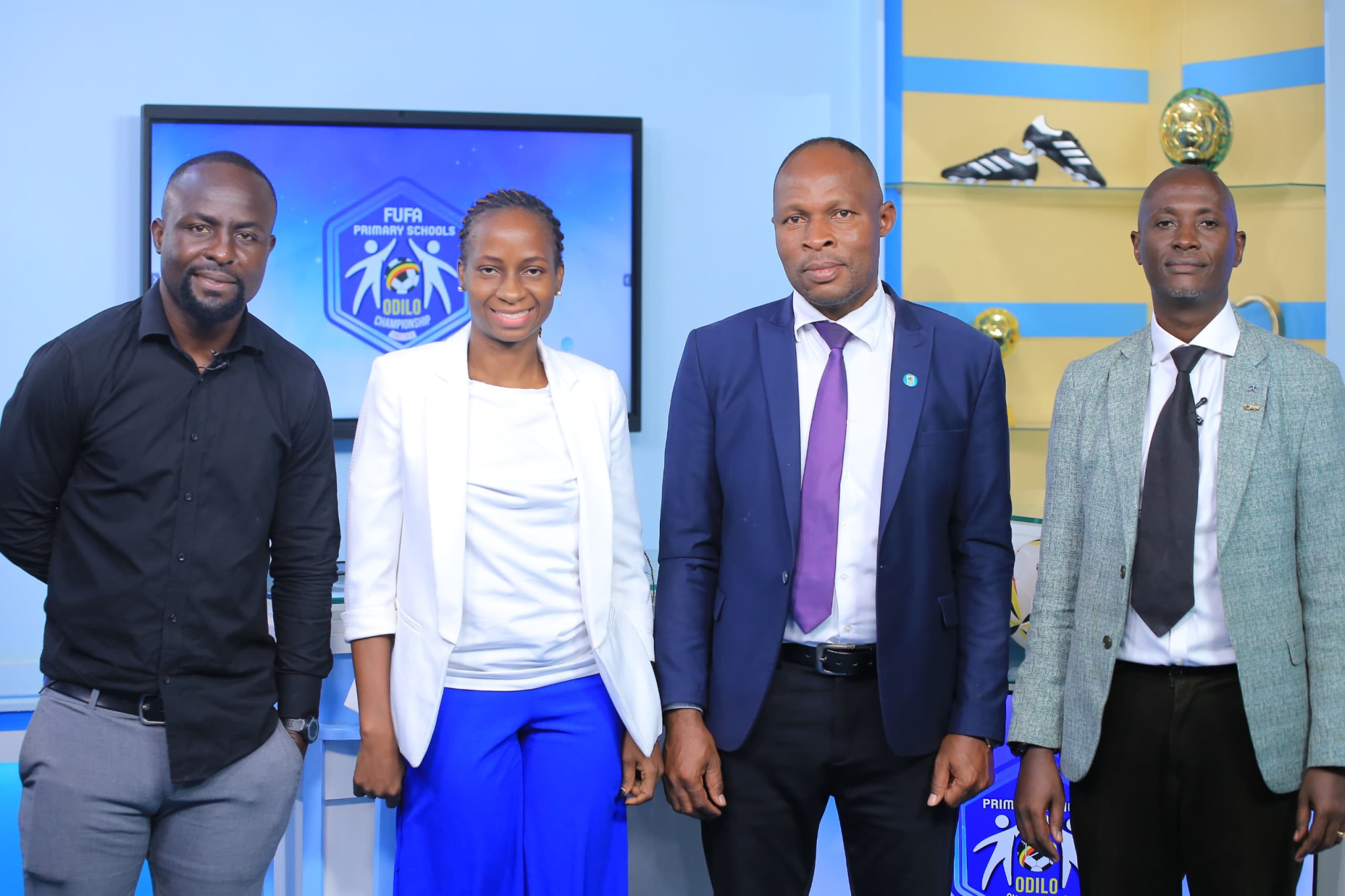 Tonny Mawejje standing on the left with three officials at a table during the FUFA 2024 Odilo Primary Schools Championship draw, November 2024.