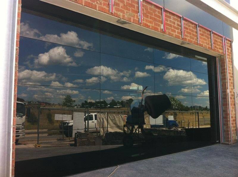 Glasslite garage door design with reflective glass panels and surrounding brickwork