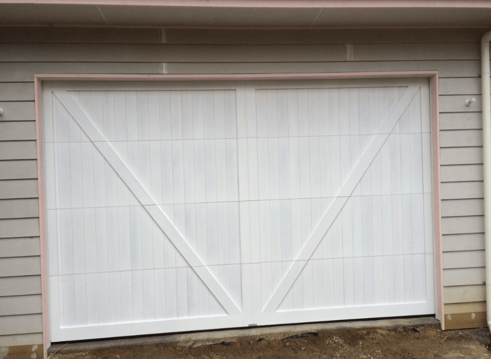 Vertical cedar garage door with overlayed boards and raised panel design