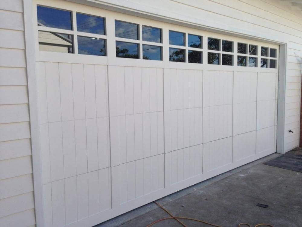 Primed carriage panel garage door with pattern windows and highlighted design.