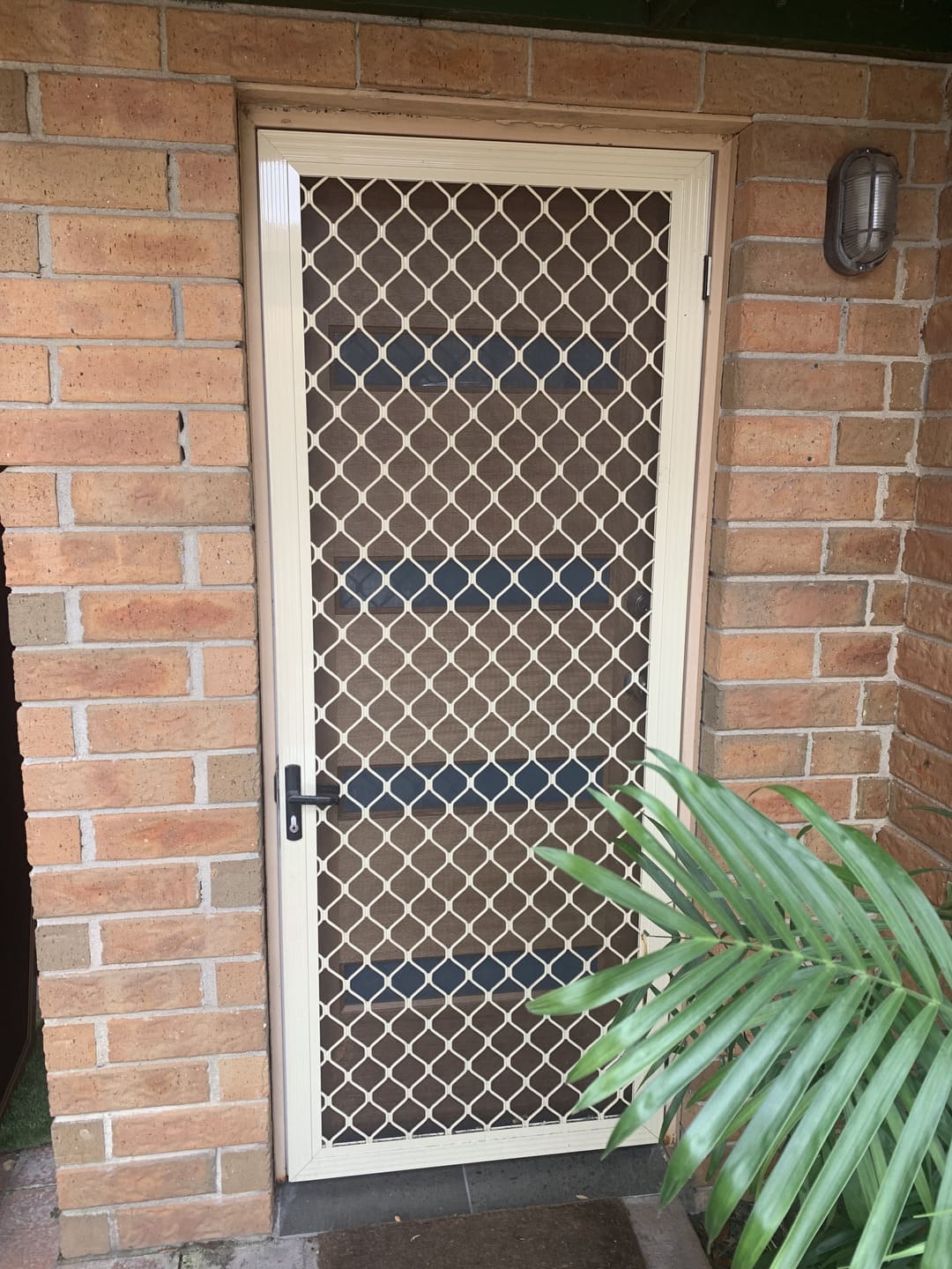 Diamond grille security screen door installed on brick home entry