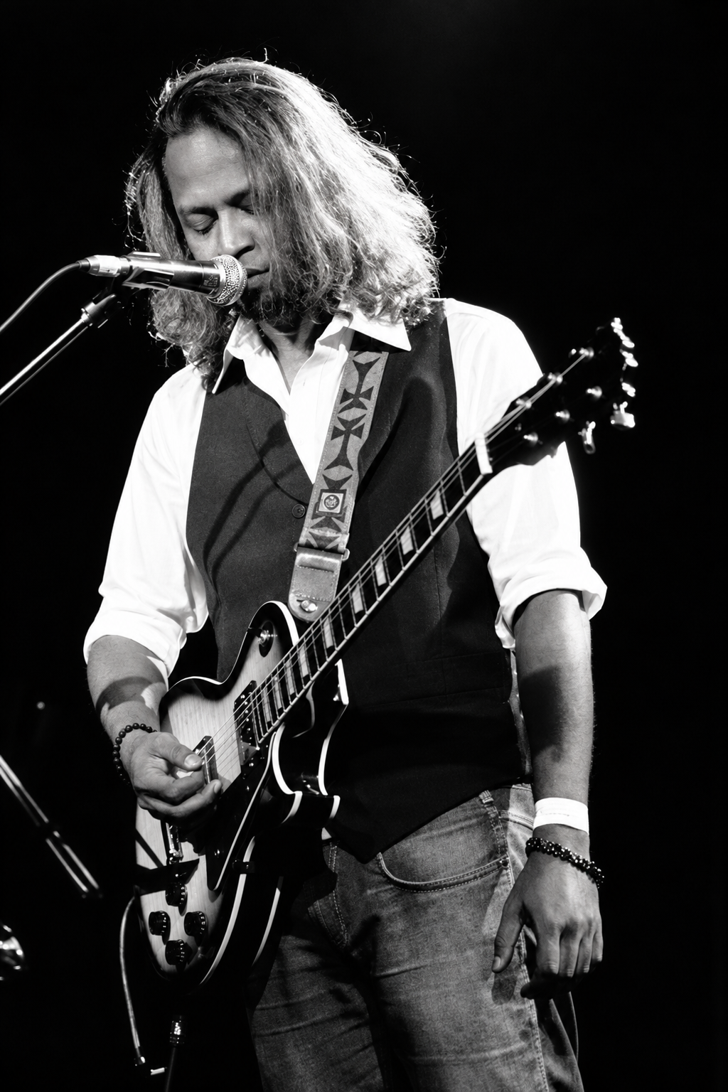The Blue Mister performing live in high-contrast black and white with electric guitar and waistcoat