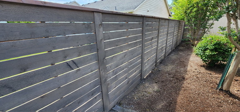 Cleanly pruned shrubs along modern horizontal cedar fence