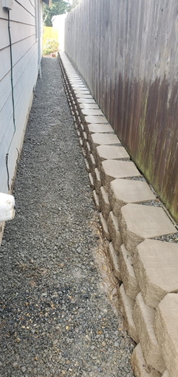 Retaining wall block installation and compacted gravel sub-base along side fence