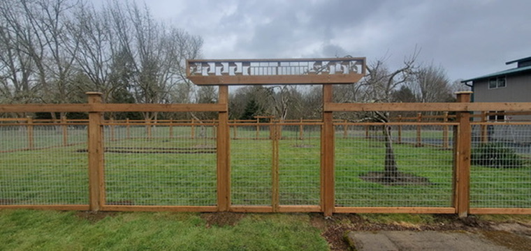 Wood and wire mesh garden fence enclosure with custom ornamental lattice header