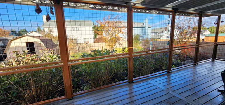 Custom cedar posts with black hog-wire railing panels overlooking lush landscaped backyard
