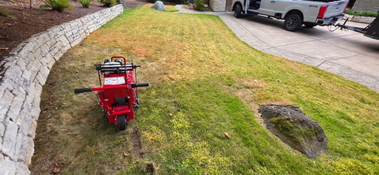 Motorized red sod cutter removing old lawn along retaining wall