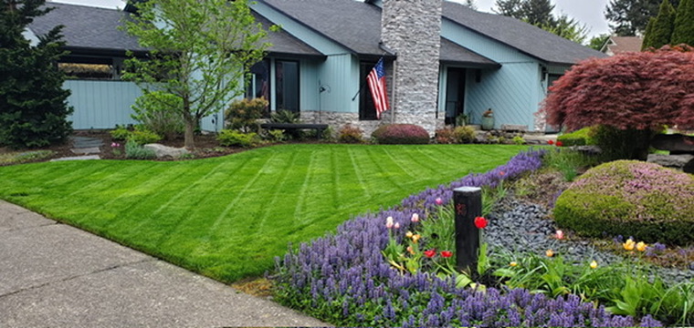 Manicured Oregon front lawn with precise mowing stripes and floral landscaping