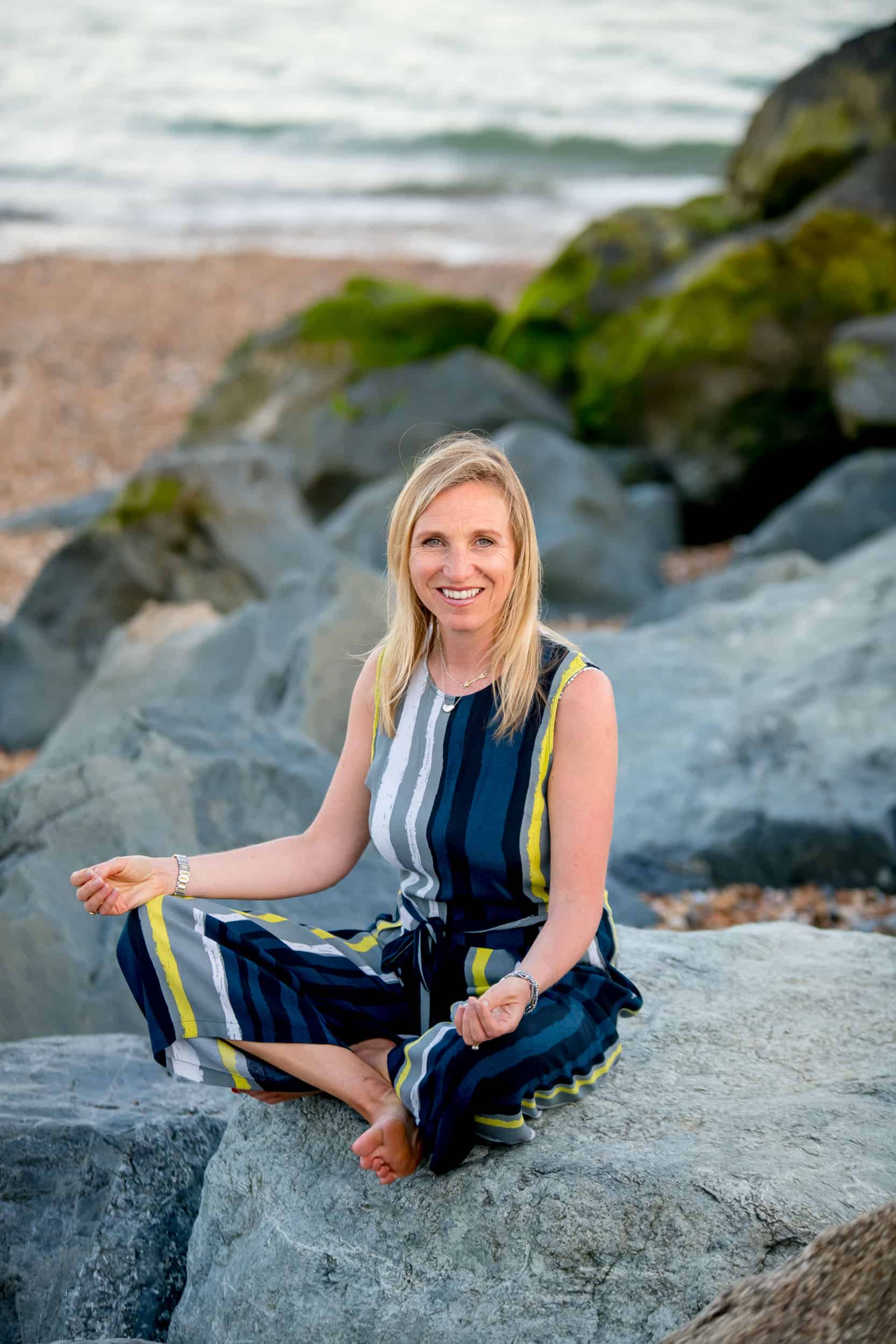 Annabel meditating on a rock by the sea