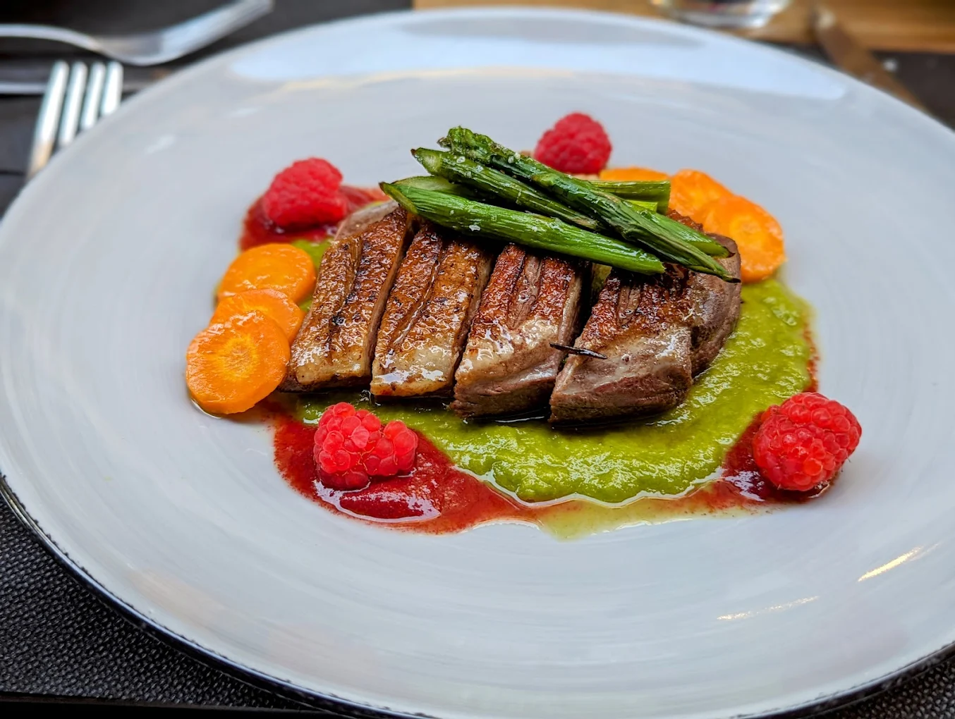 Petto d'anatra laccato con asparagi, carote e coulis di lamponi