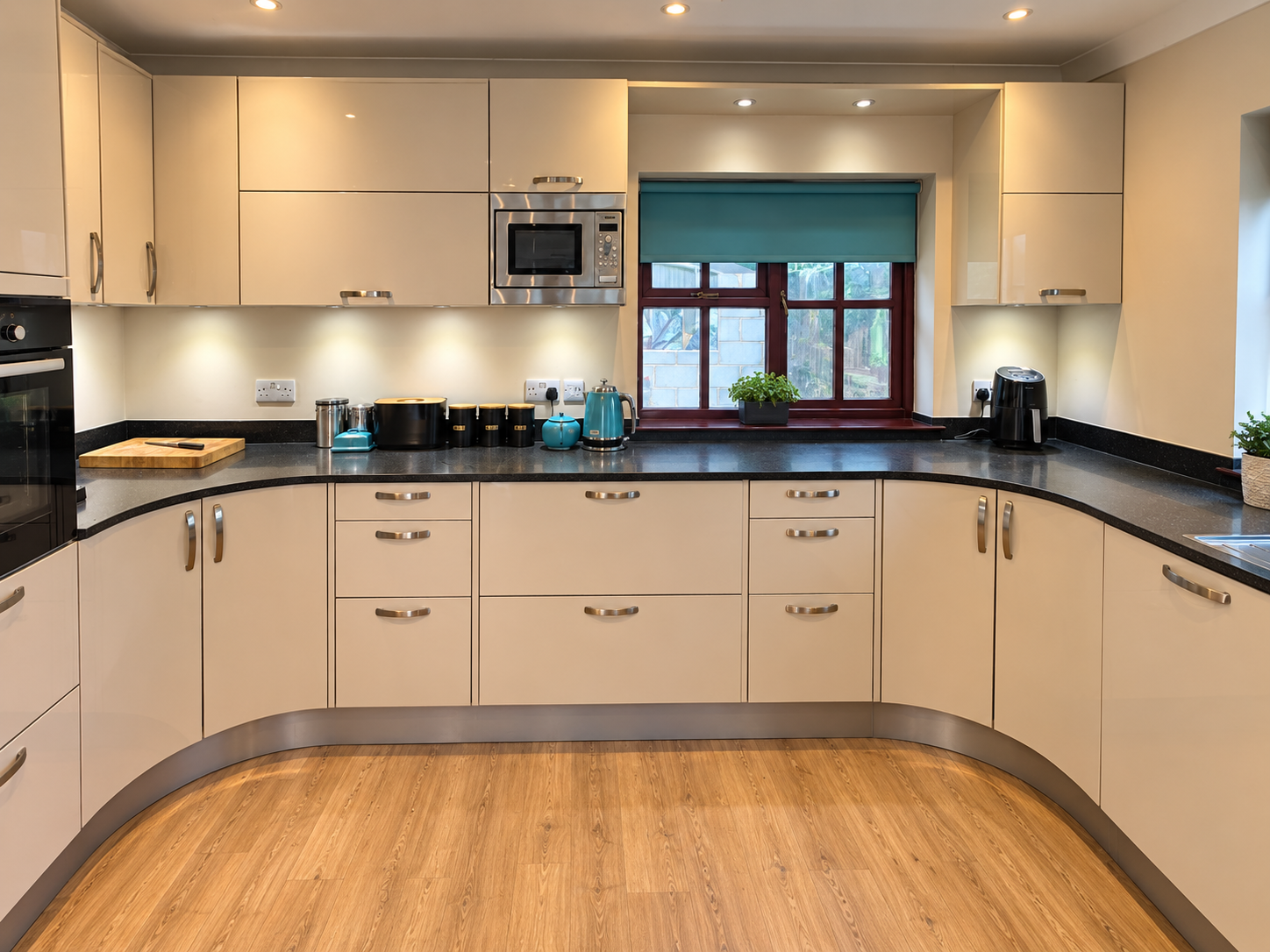 Curved soft cream kitchen cabinetry with black granite worktops in Cuckfield