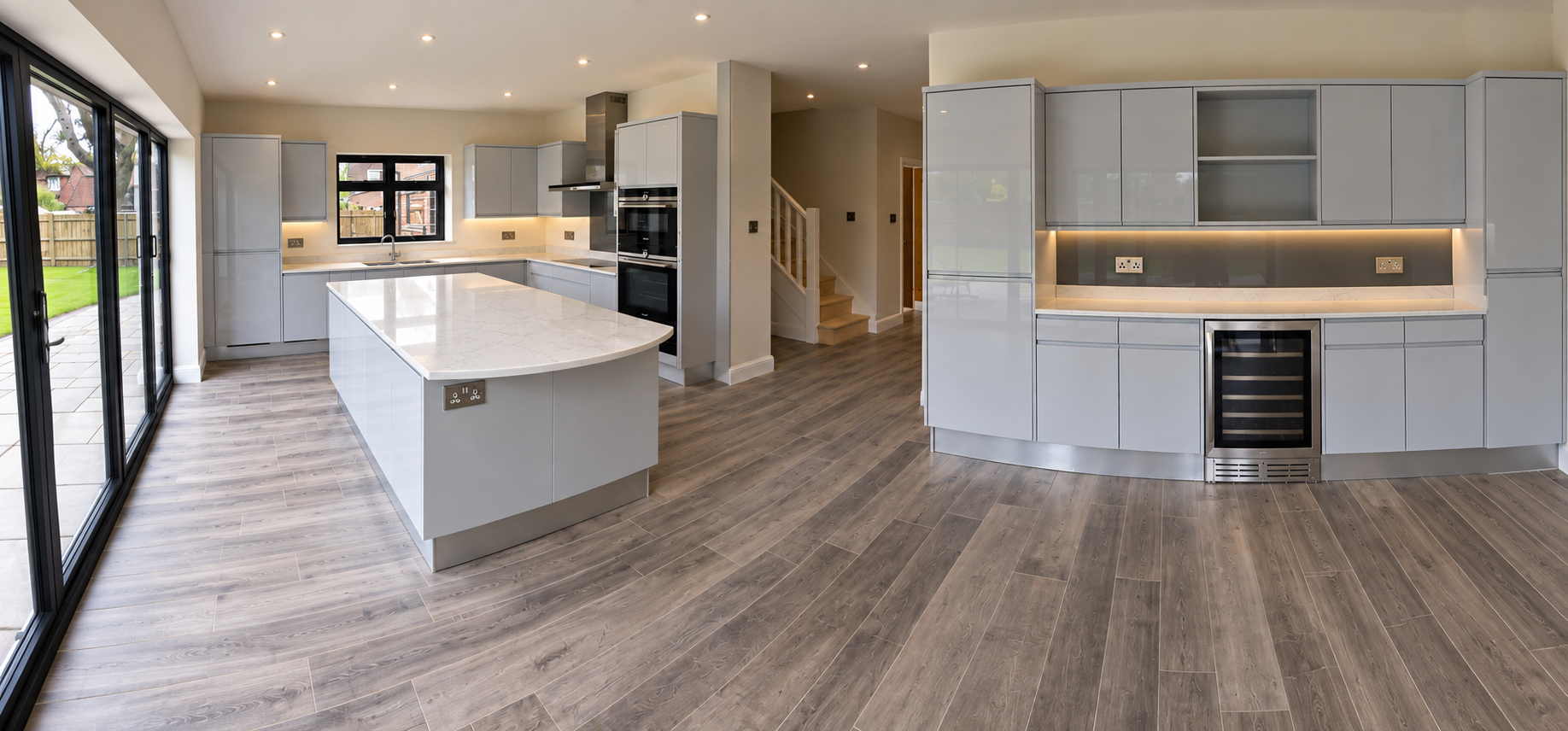 High-gloss dove grey kitchen with curved island and wine cooler in Haywards Heath