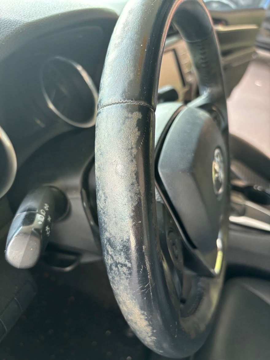 Steering wheel before detailing showing grease, oil, and worn surface