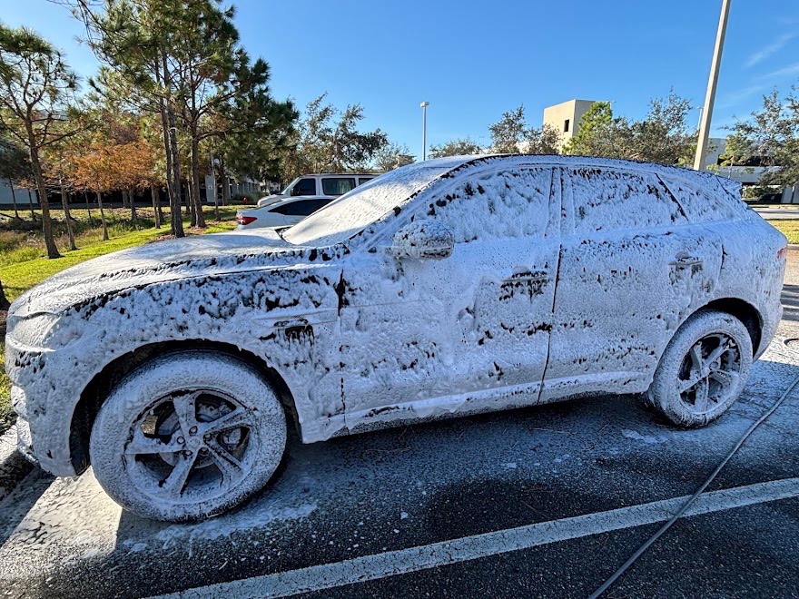 Luxury SUV blanketed in thick white snow foam pre-wash