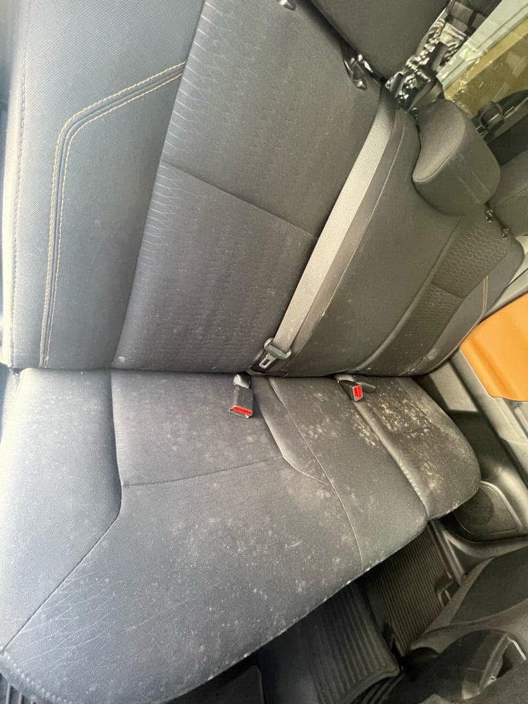 Vehicle cloth back seats before shampoo extraction covered with dust, stains, and debris
