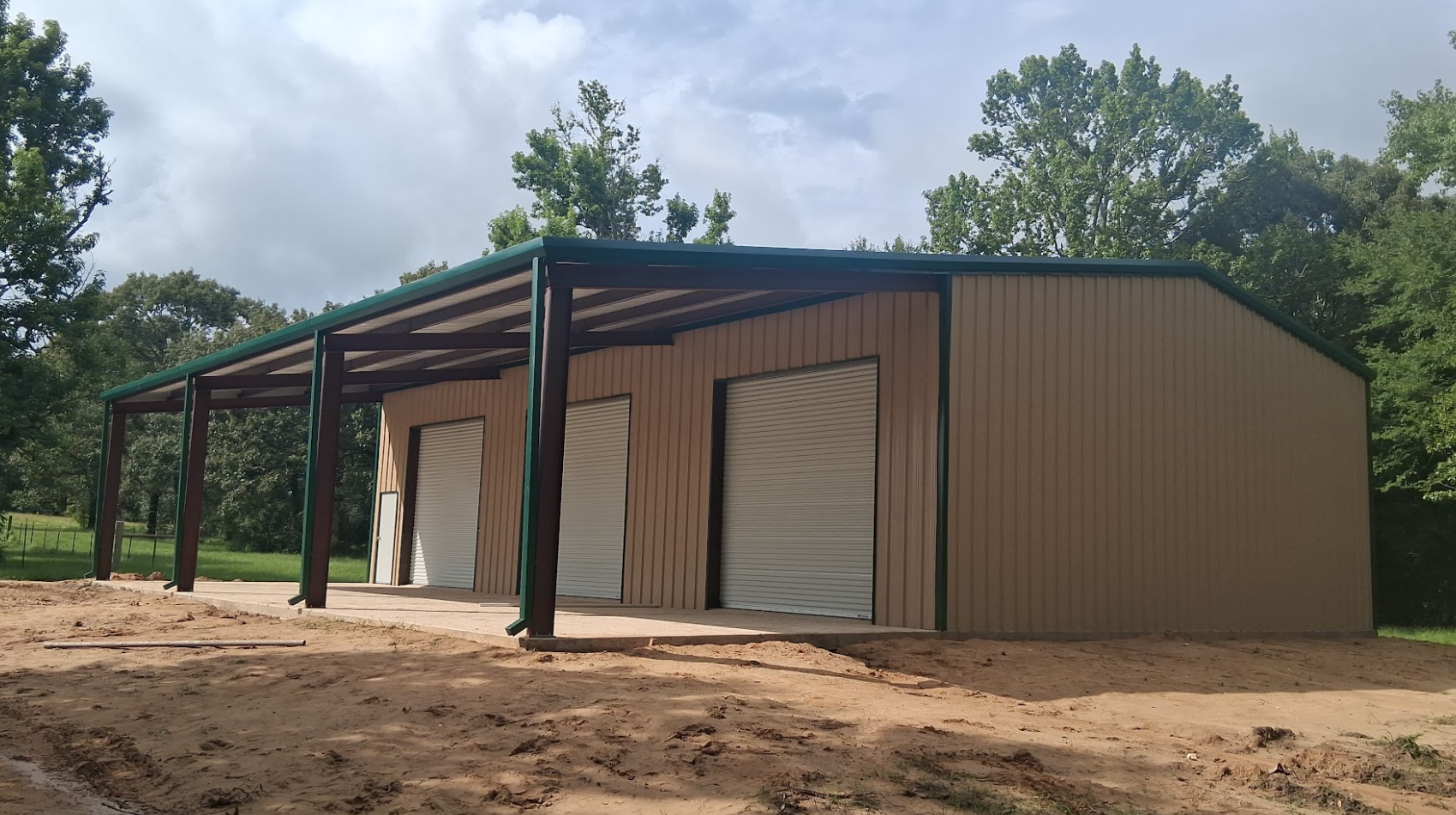 Custom tan steel shop with green trim & covered overhang