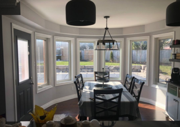 Curved dining bay windows overlooking backyard patio before custom shutters