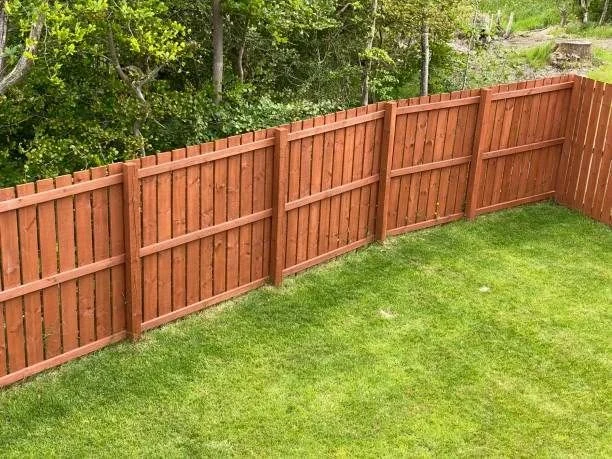 Wood privacy fence along a lawn.