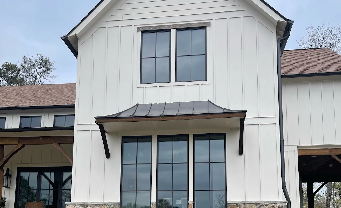Architectural dark metal window awning on board-and-batten home