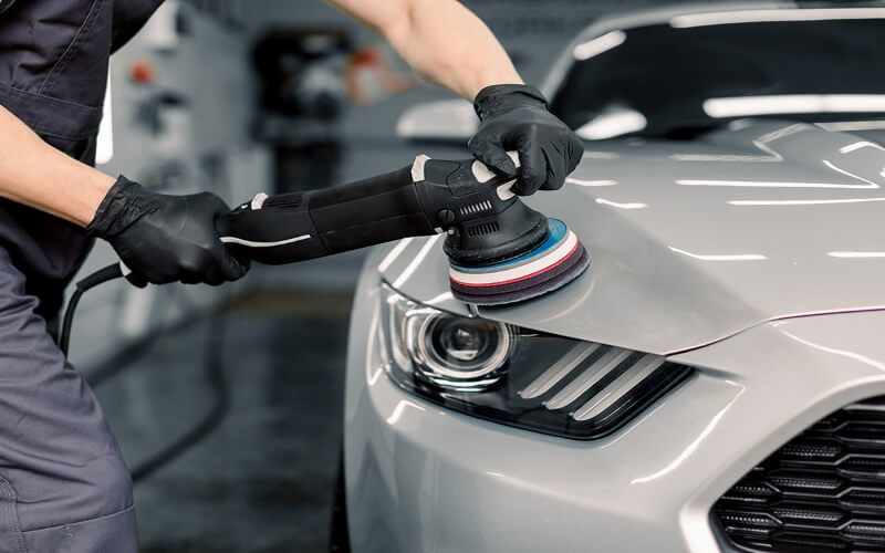 Dual-action machine polishing paint correction on silver luxury car