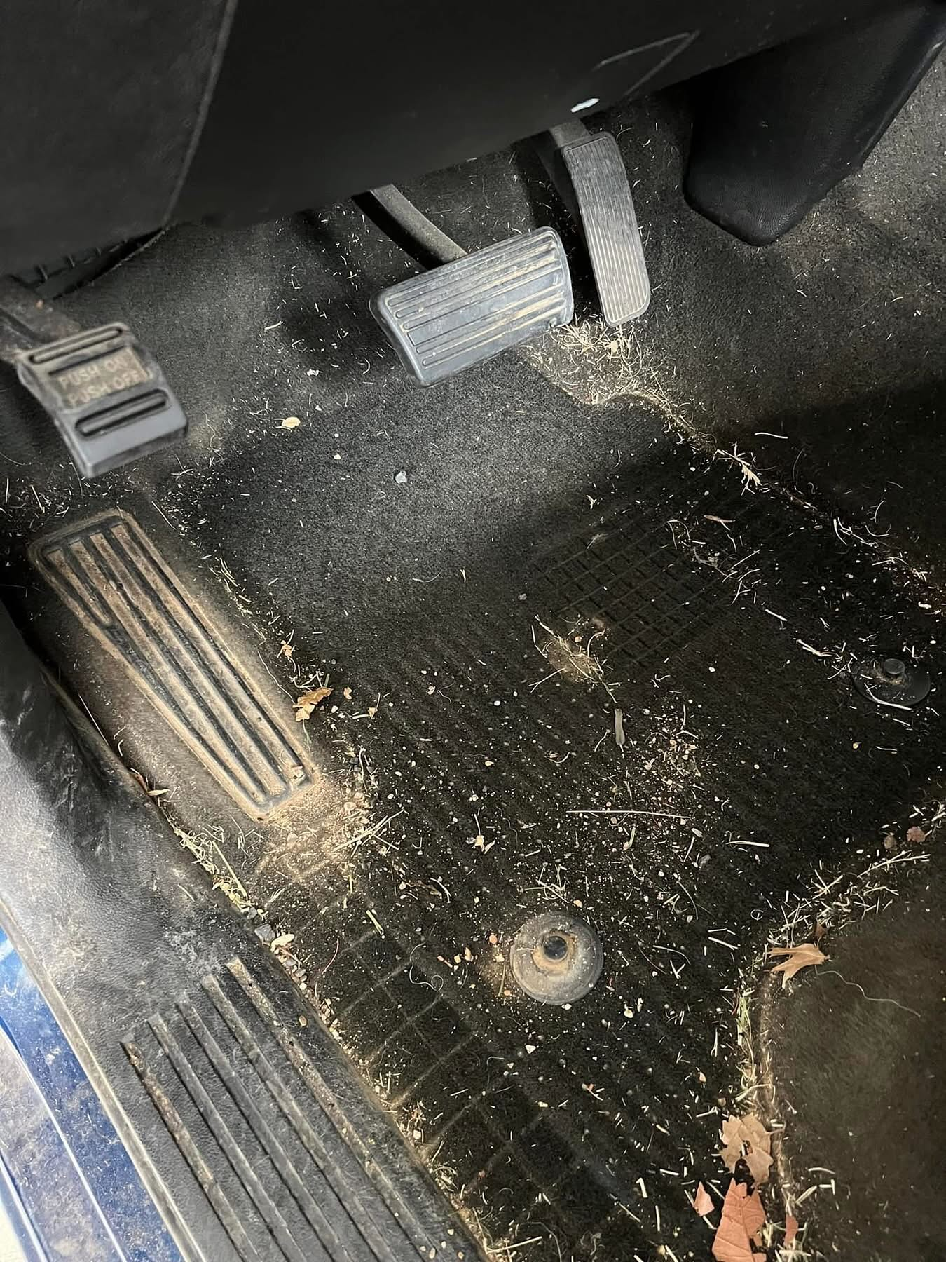 Dirty vehicle driver footwell before interior cleaning