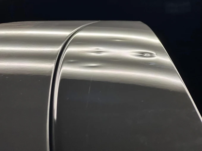 Multiple dents visible across a vehicle panel during hail damage inspection