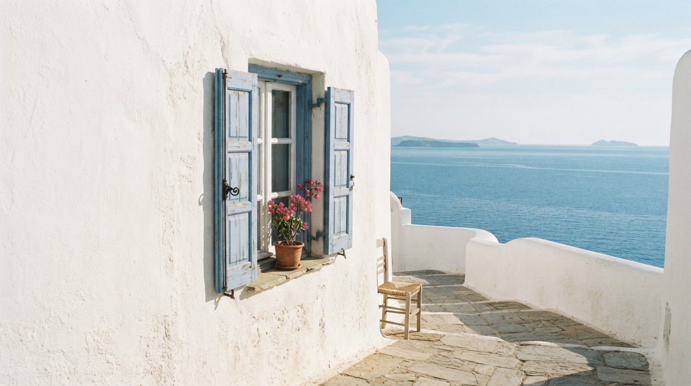 Whitewashed Cycladic walls with soft blue shutters and a glimpse of clear Aegean sea beyond, warm muted sunlight
