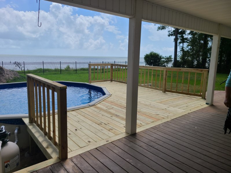 Covered porch deck looking out across swimming pool and coastal bay waters by Protech Decks