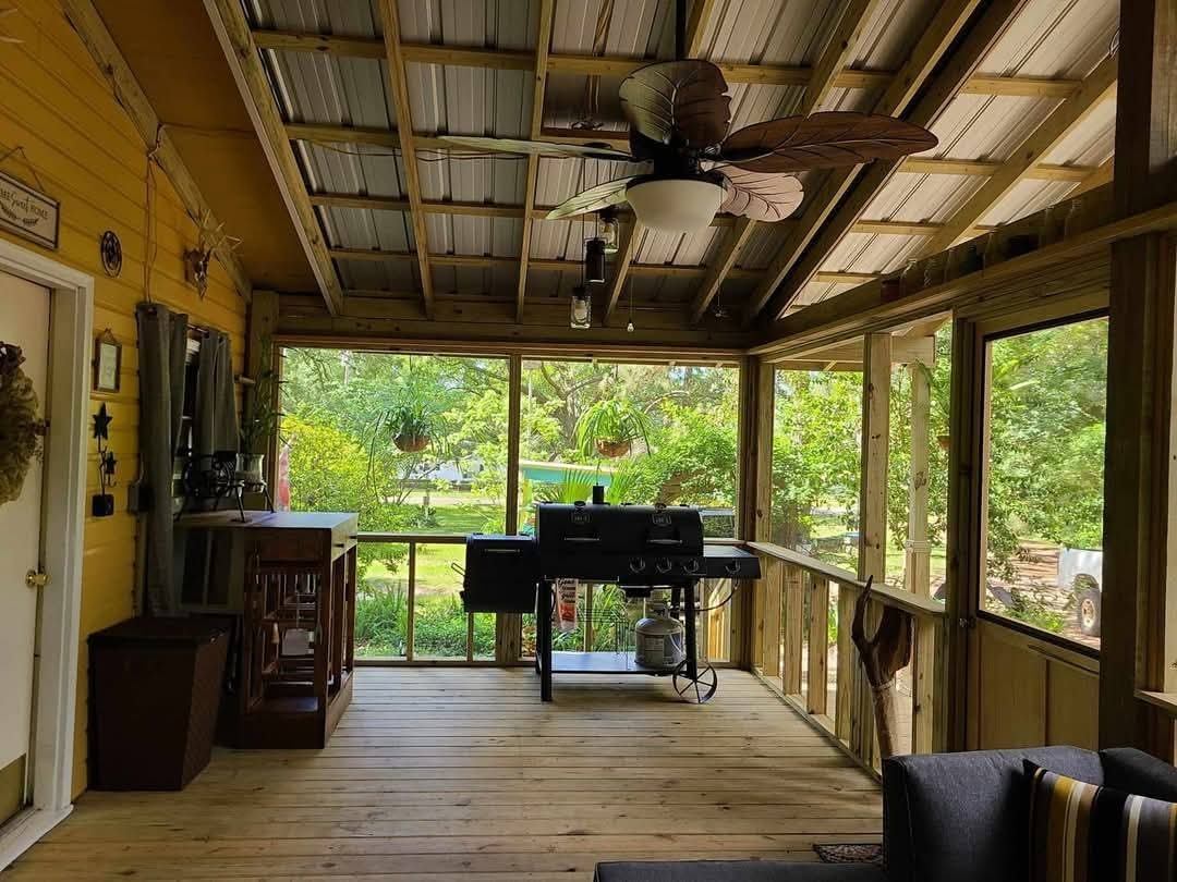 Screened-in patio enclosure with open-beam ceiling, ceiling fan and outdoor kitchen area built by Protech Decks
