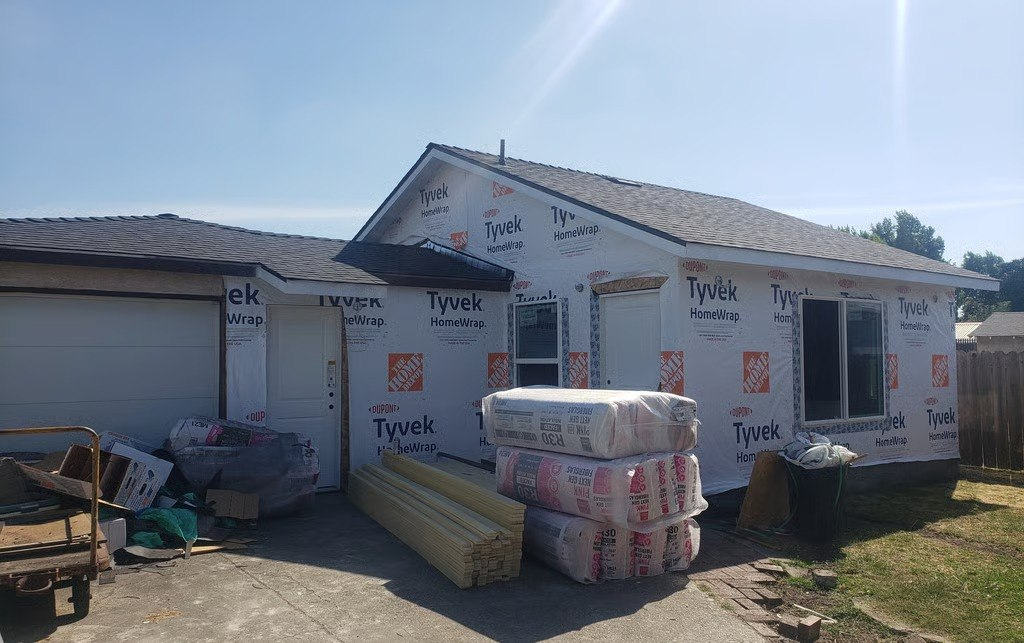 Before — new structural addition mid-framing with exposed lumber and materials staged onsite, San Leandro CA