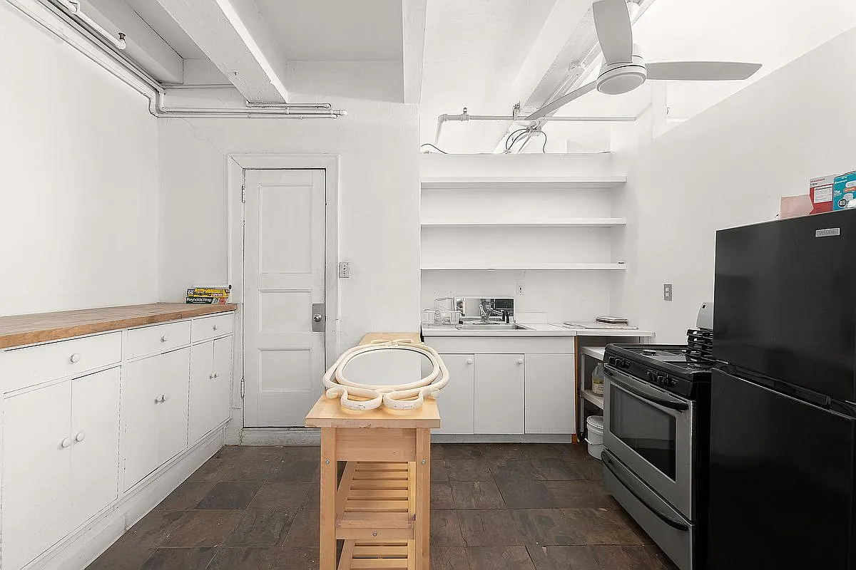 Current loft kitchen with white cabinetry, butcher block prep station and open shelving