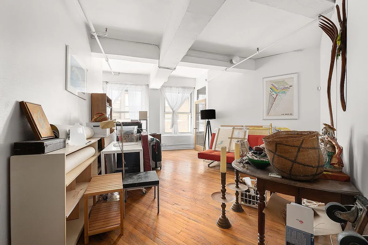 Spacious studio living room showing original pine floors, beams and dual windows
