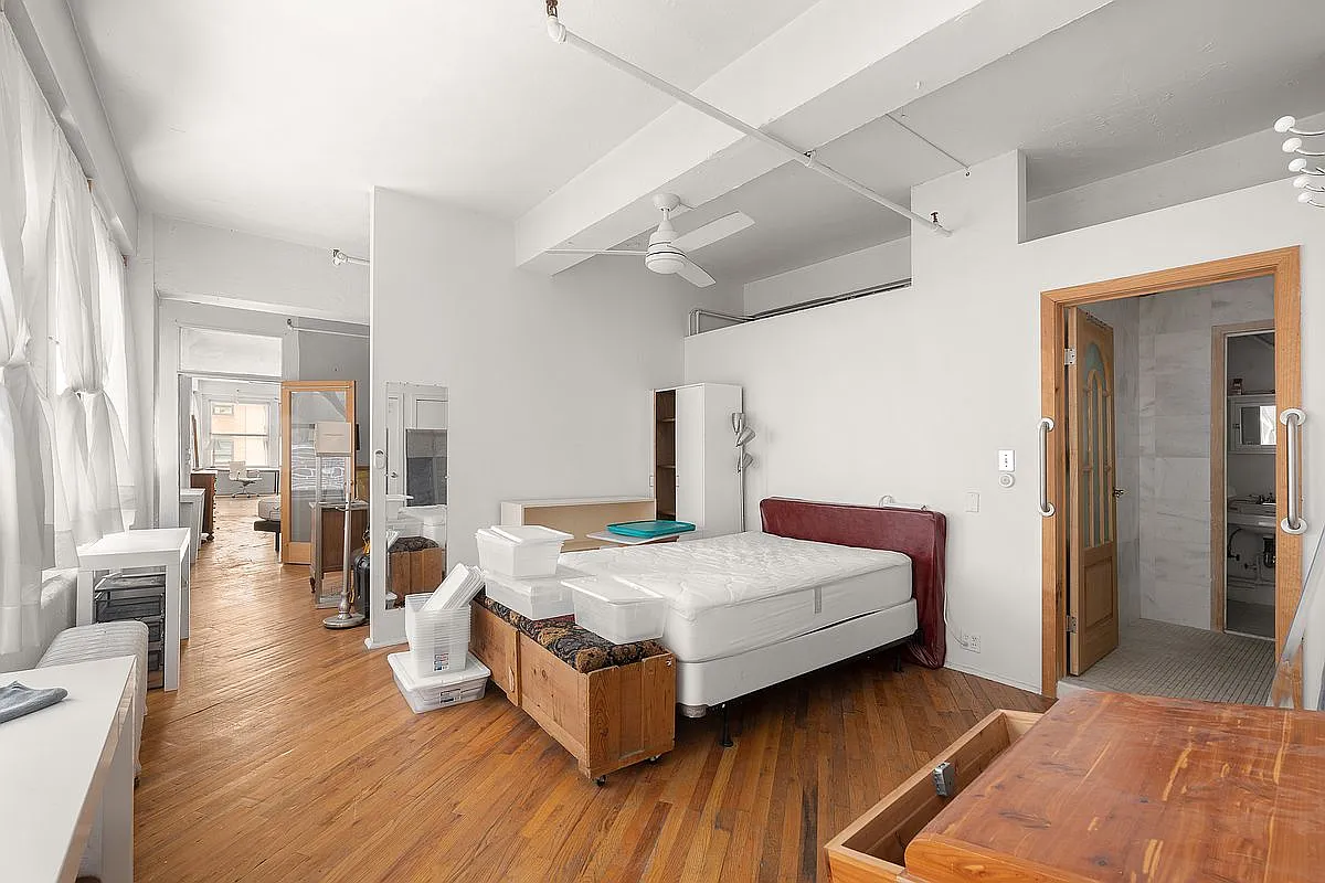 Current primary bedroom area with herringbone/diagonal wood floors and bath access