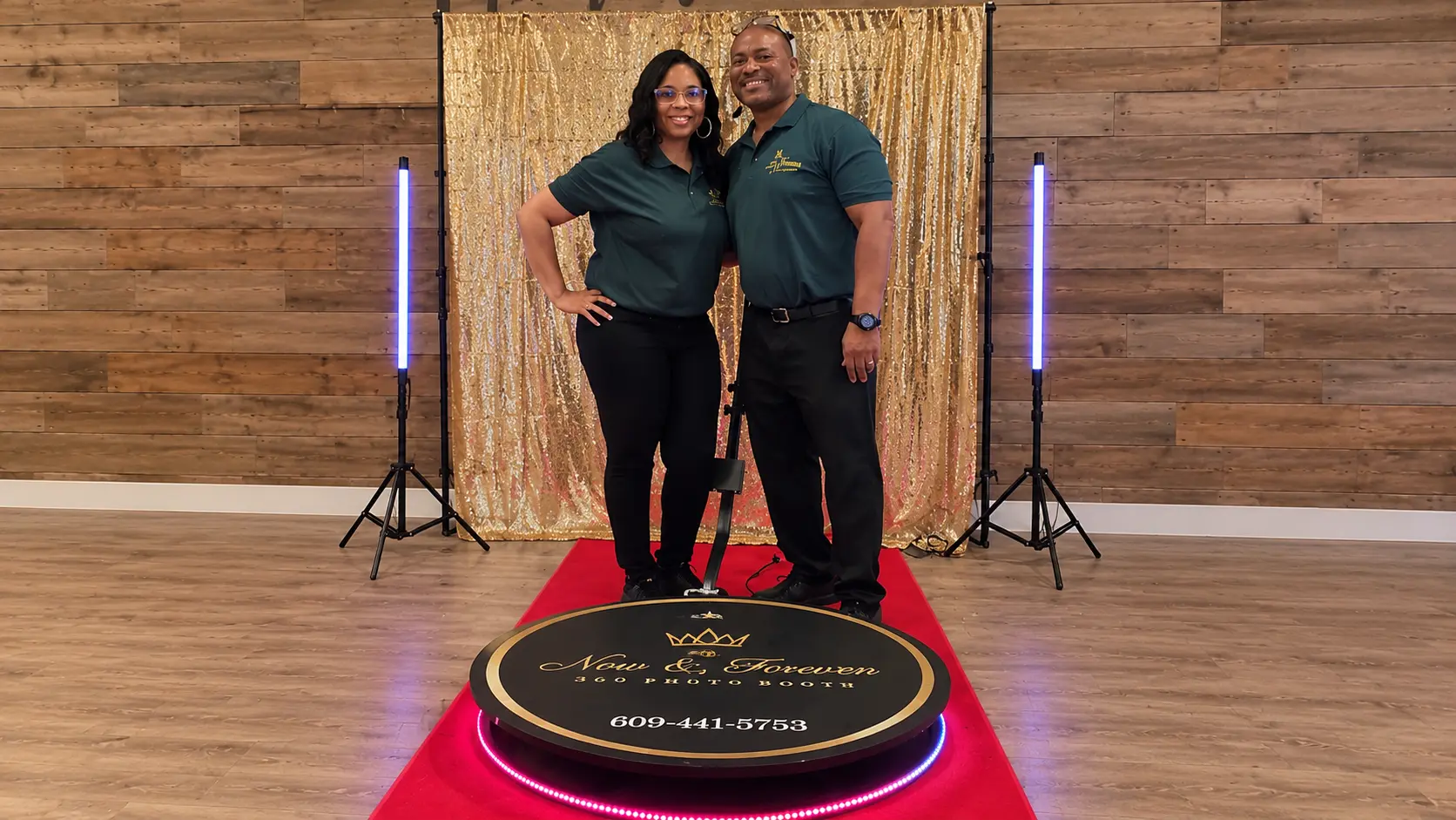 Now & Forever 360 Photo Booth attendants standing with the branded 360 platform, VIP red carpet, glowing LED pillars, and gold sequin backdrop
