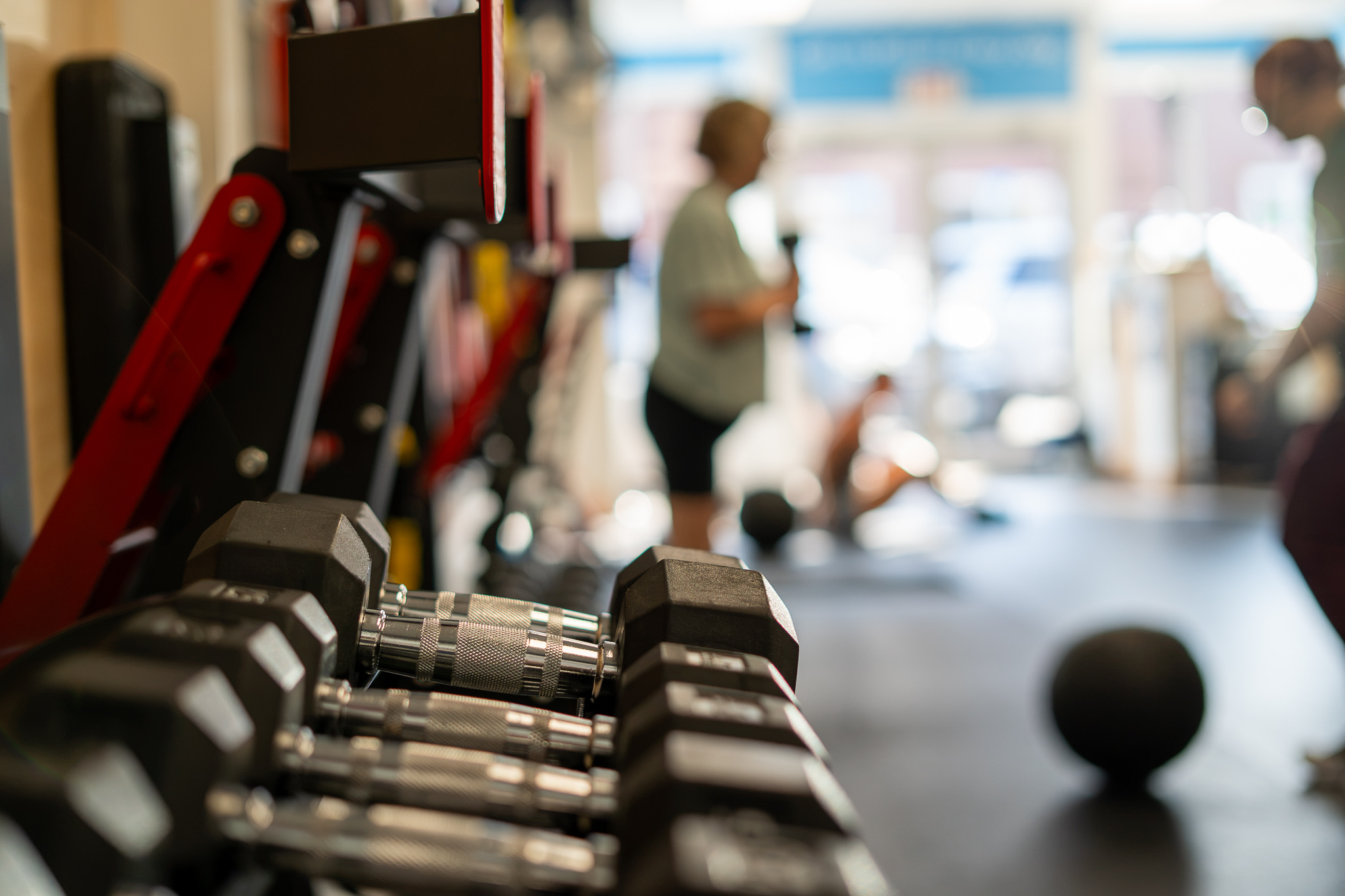 Dumbbells and clean training floor with members in session at Adam Clark Fitness, Brewer, ME
