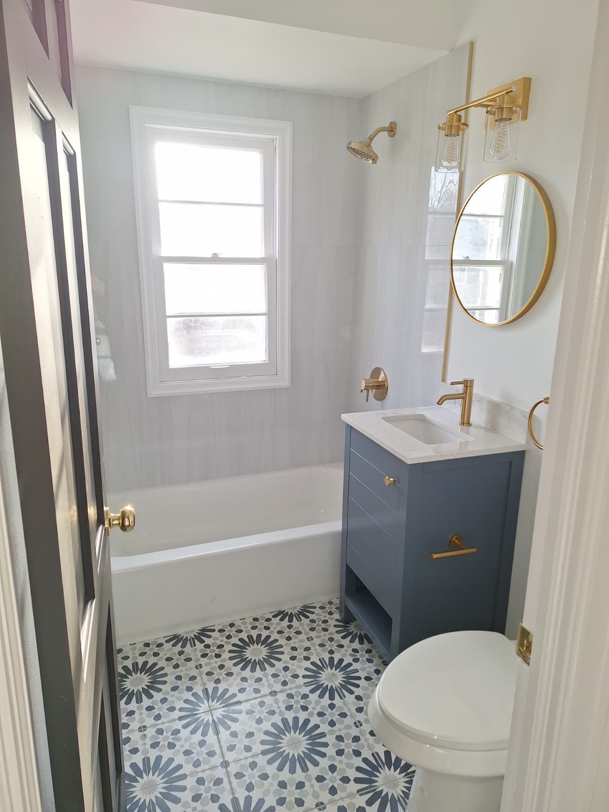 Custom bathroom remodel with navy vanity and gold fixtures