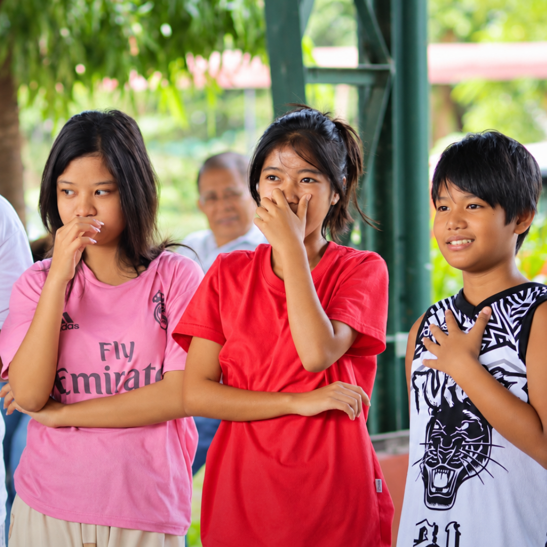 Young participants in bright shirts smiling together during a gathering at Omura Homes.