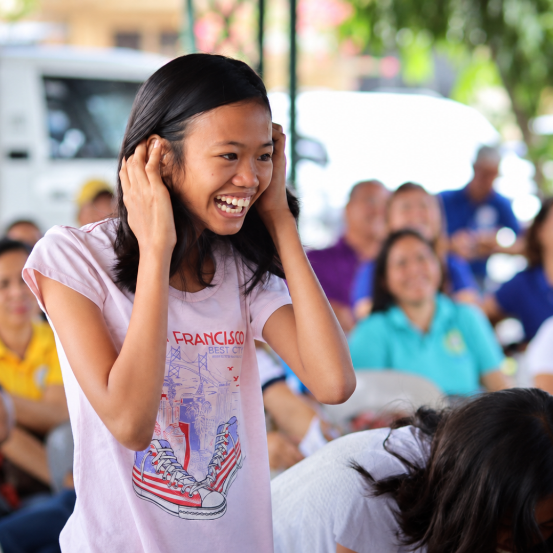 A smiling young girl laughing cheerfully during a community gathering.