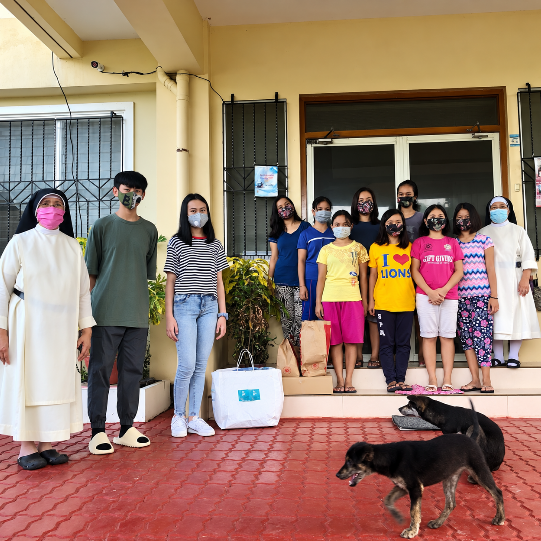 Volunteers and sisters standing with care packages outside Omura Home.