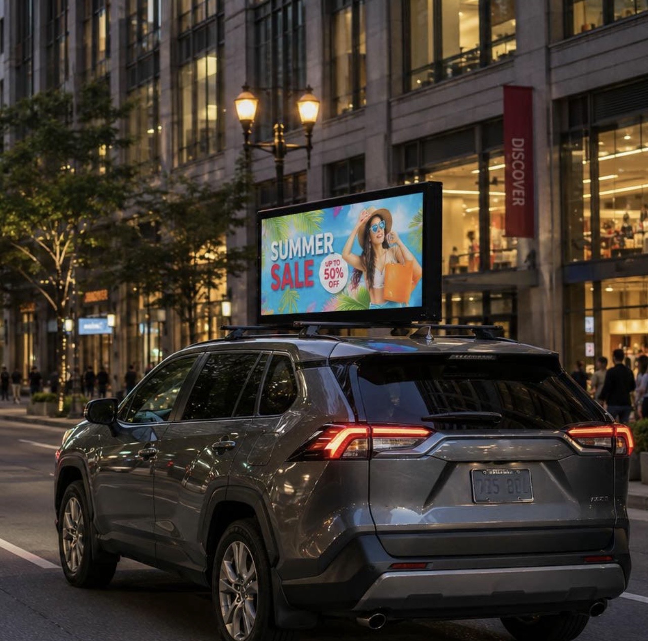 Vehicle with rooftop digital LED billboard display driving on South Florida street at dusk promoting a local business