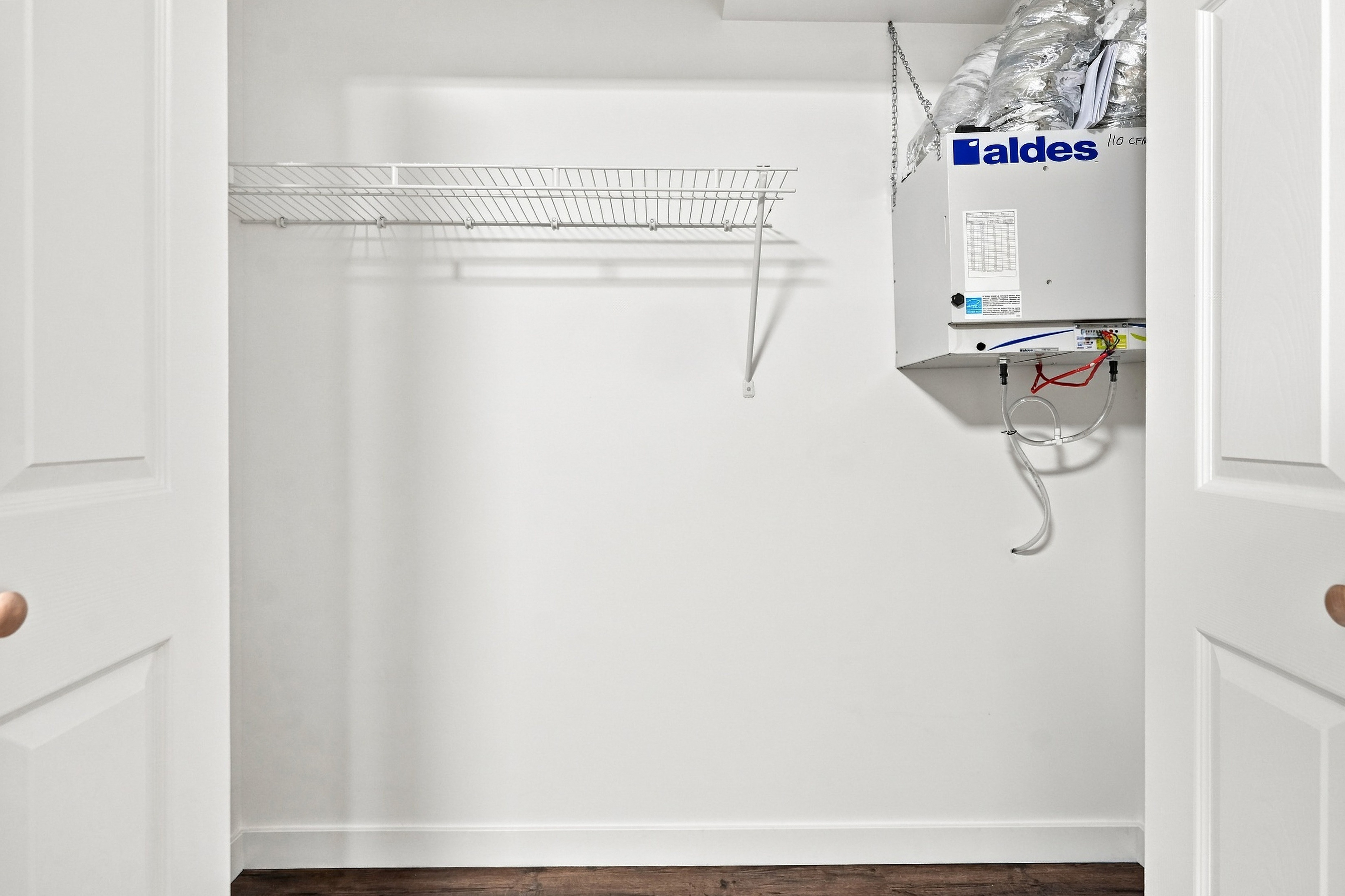 Bedroom closet with ventilation unit and upper wire storage shelf