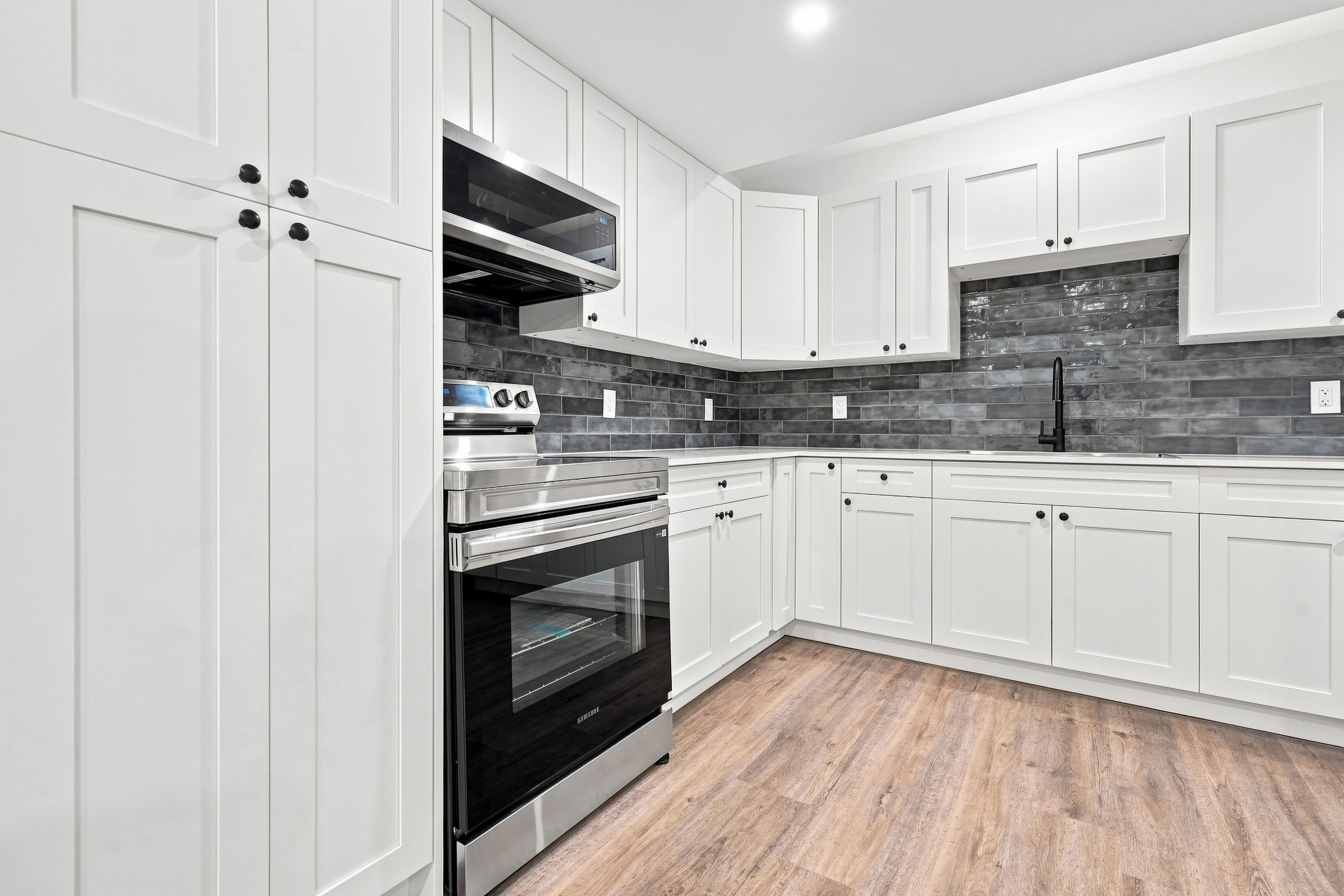 Brand-new kitchen with quartz countertops, tile backsplash, and stainless appliances