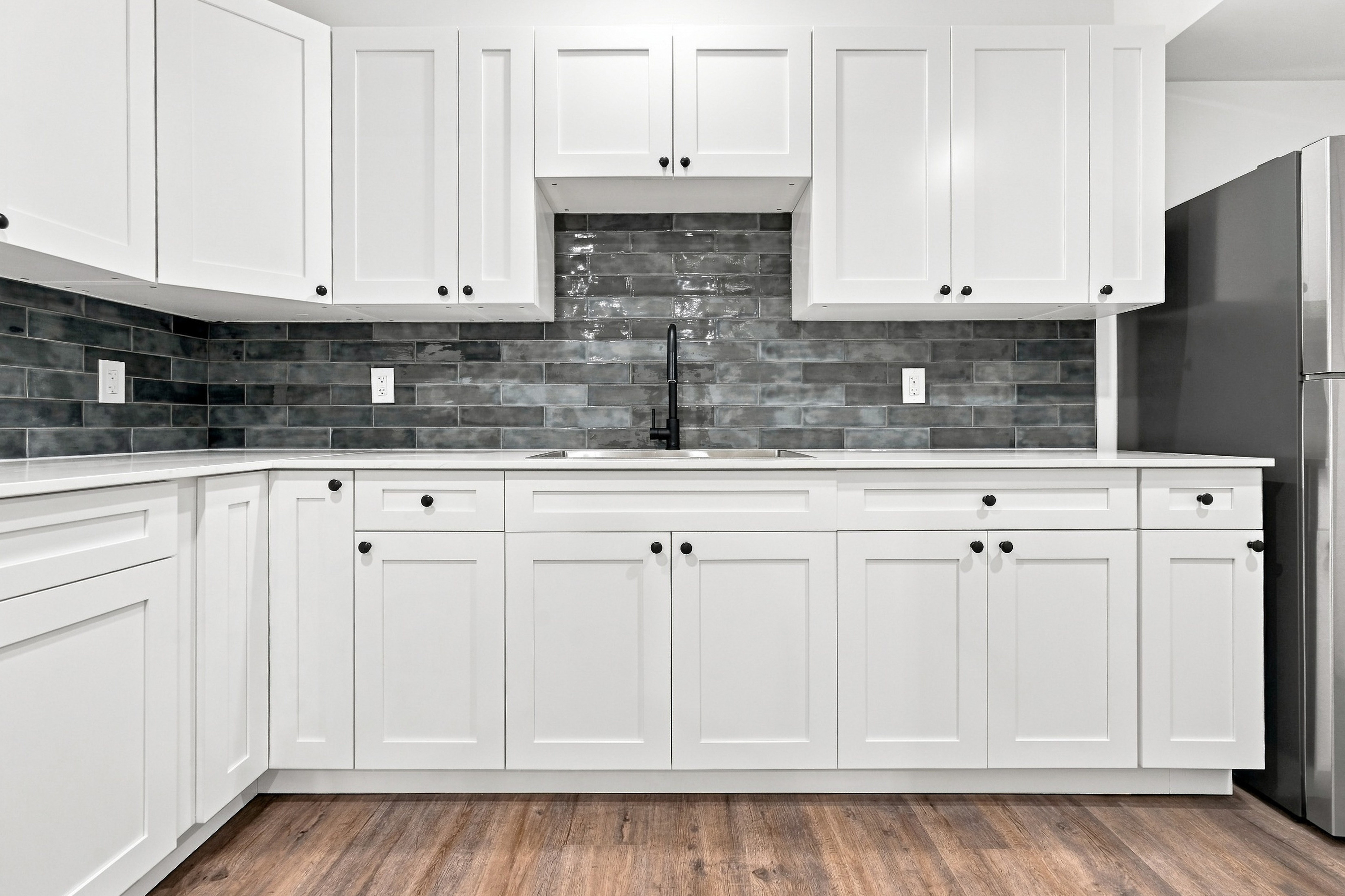 Kitchen cabinetry, quartz countertops, and modern tile backsplash