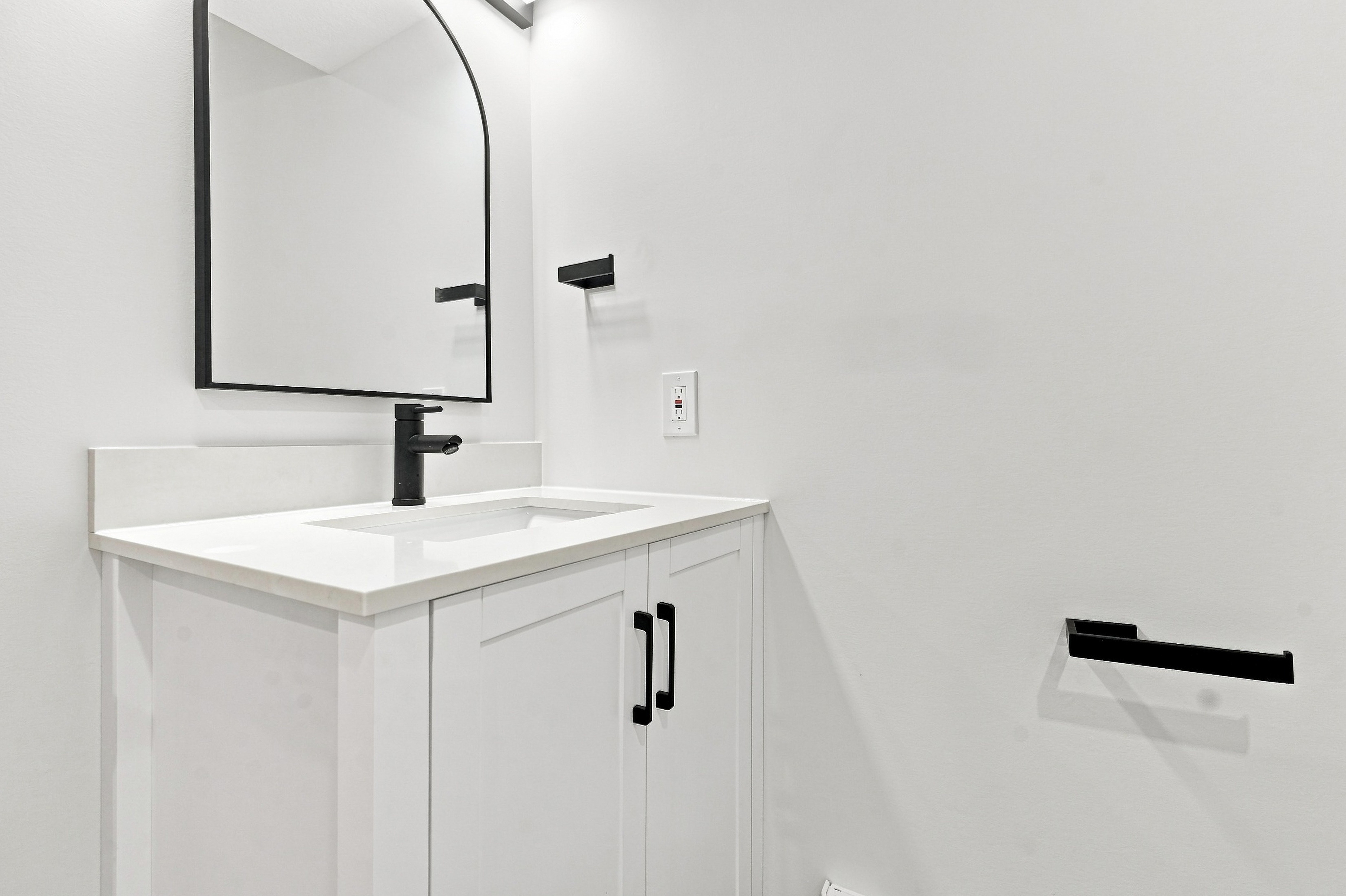 Brand-new 3-piece bathroom with quartz vanity, matte black fixtures, and arched mirror
