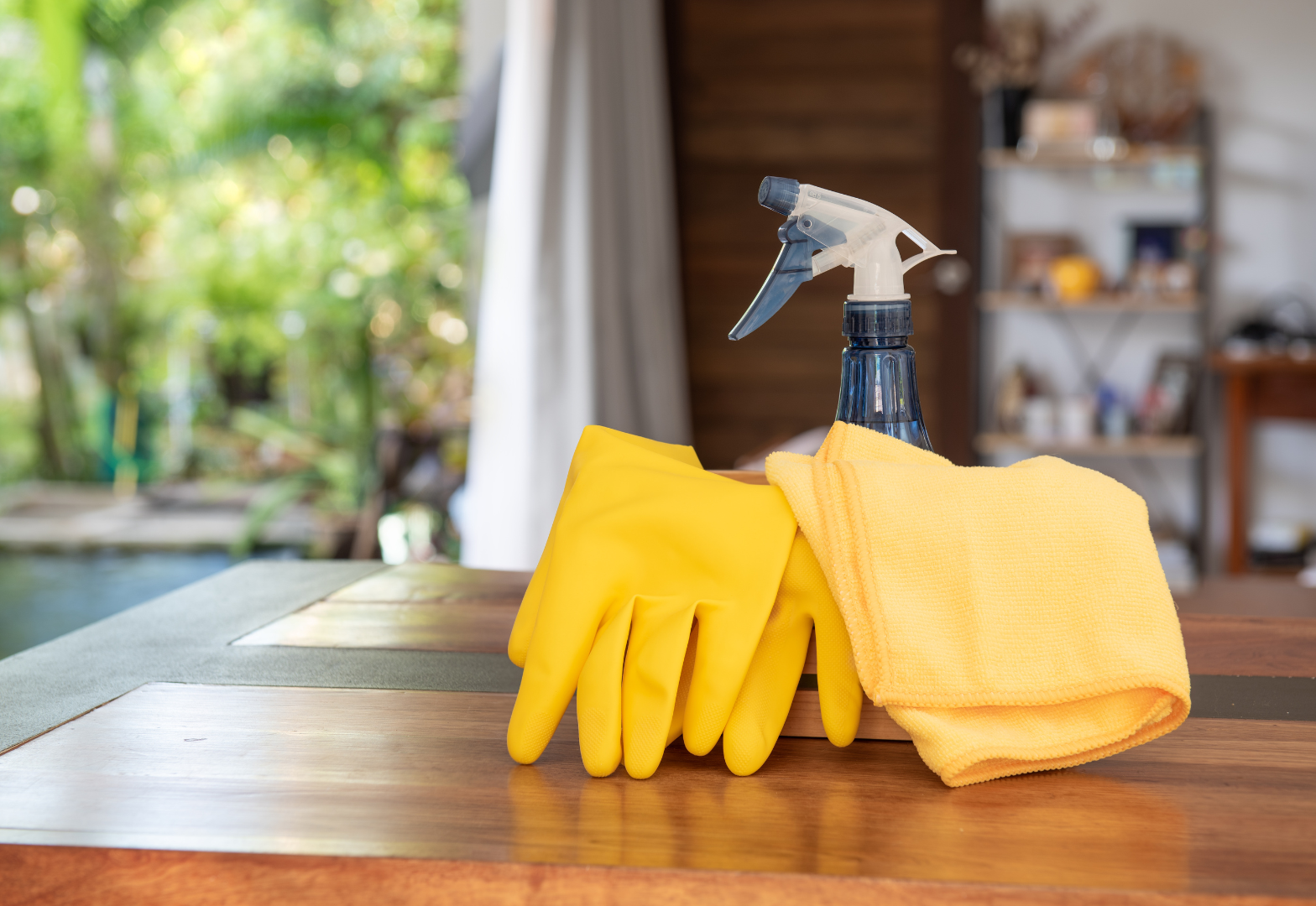 Yellow rubber gloves, spray bottle and yellow cloth on table
