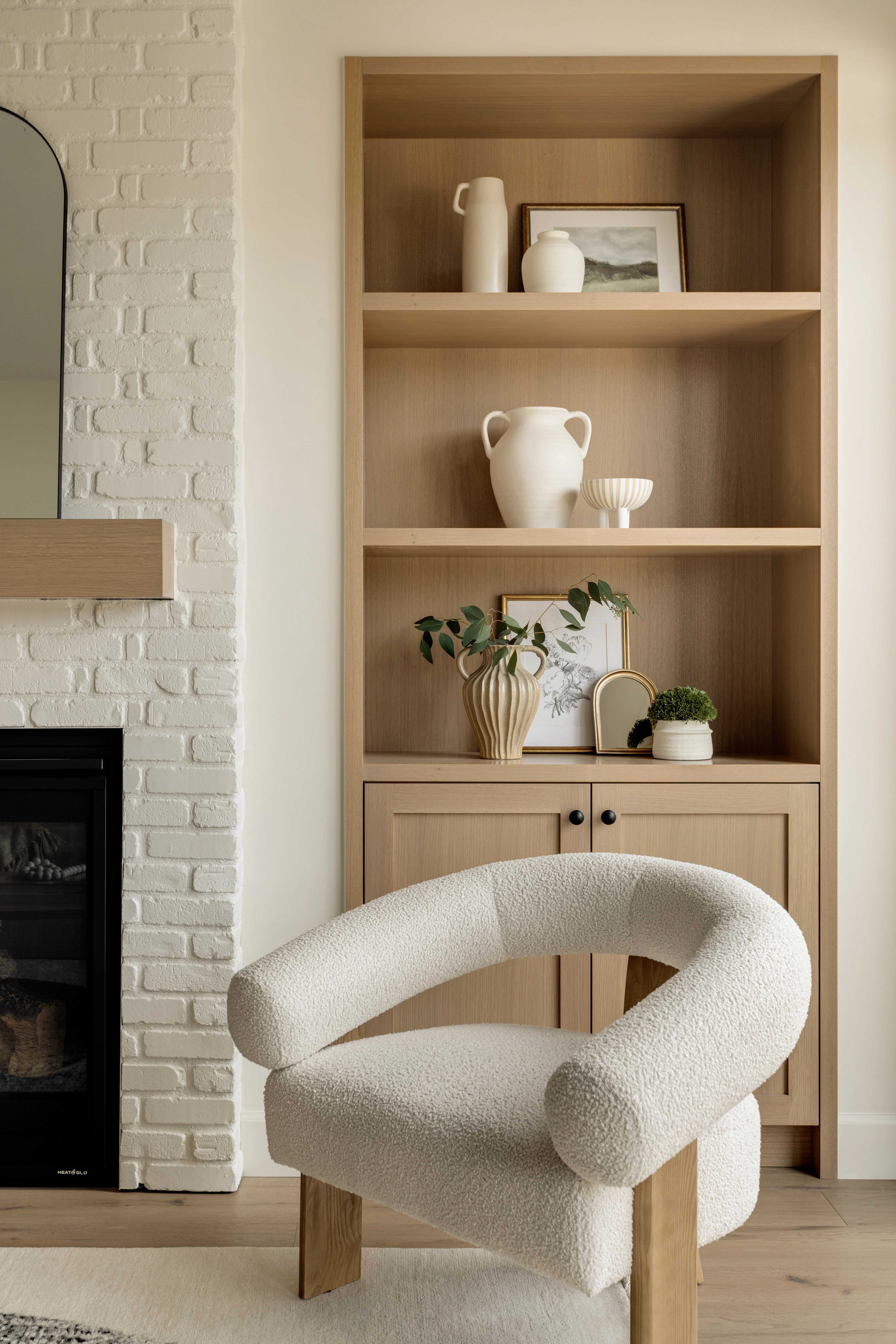 Living room with white brick fireplace, custom oak built-in shelving and bouclé armchair in Capitol Hill custom infill by Bright Custom Homes