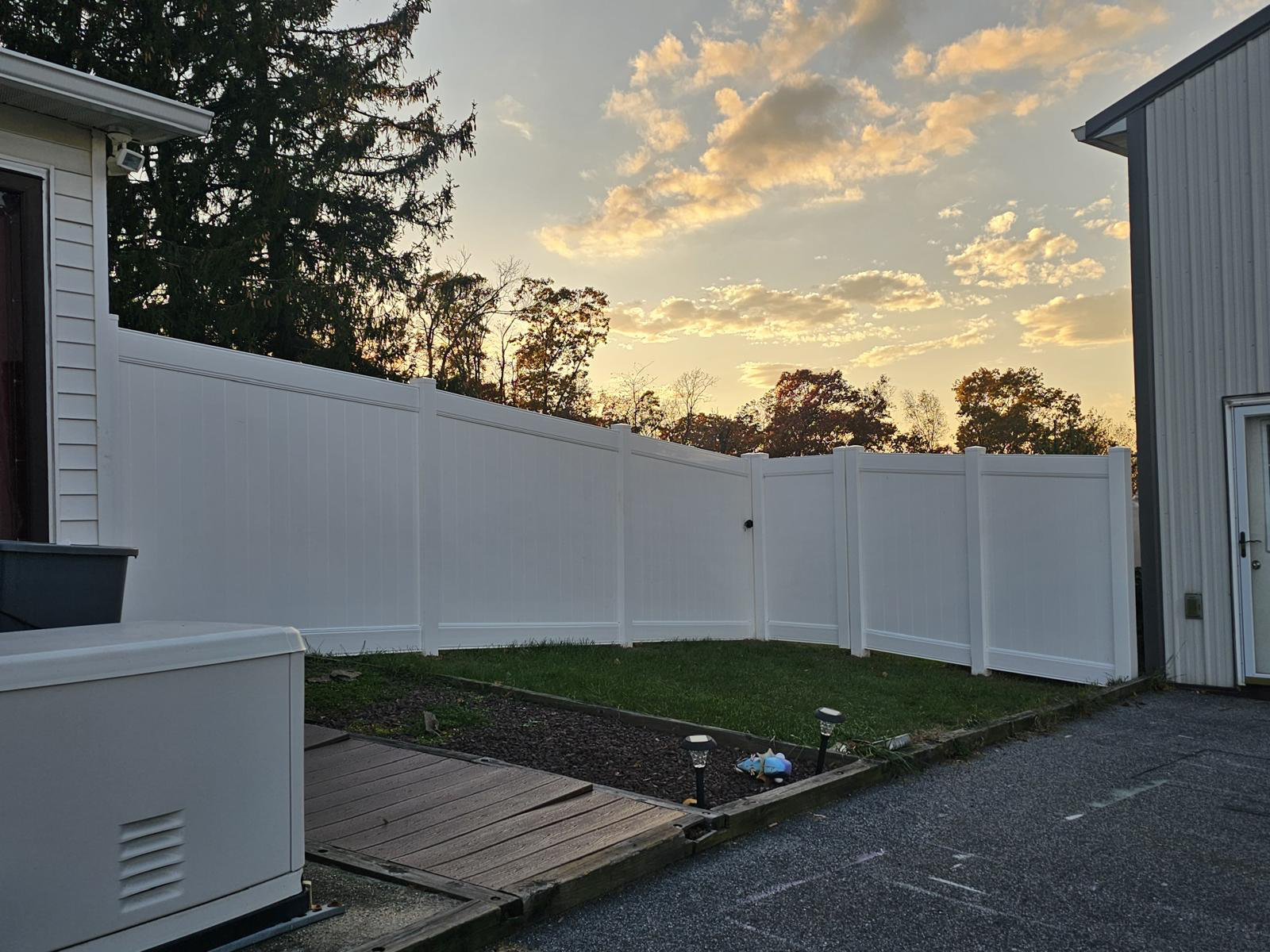 White vinyl privacy fence enclosure installed by JA Fencing LLC at sunset