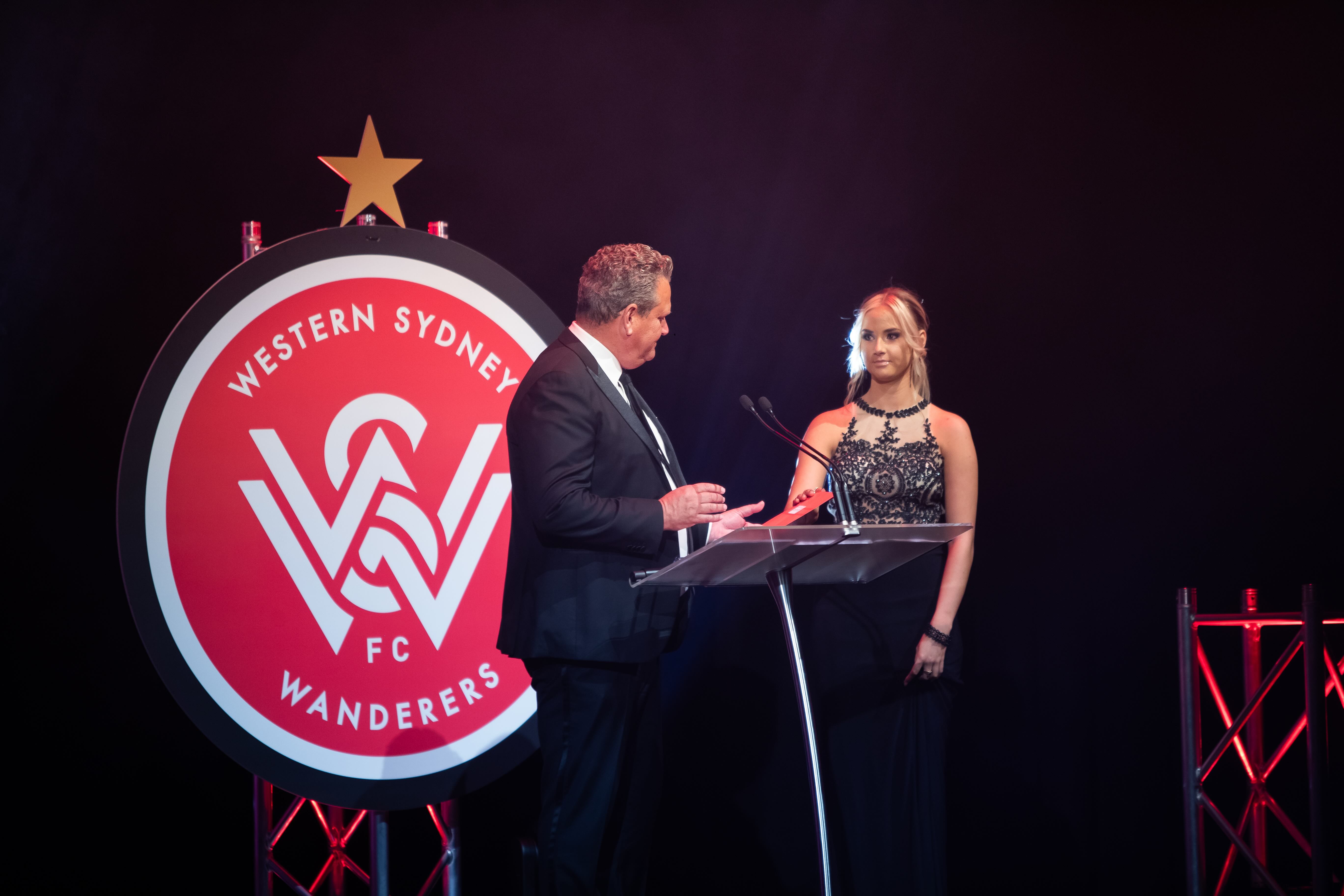 Western Sydney Wanderers FC awards gala stage with custom circular logo backdrop and presenters at lectern
