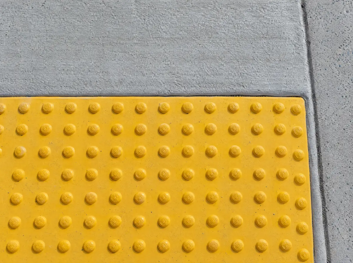 Close-up of a yellow truncated-dome detectable warning panel set in new concrete